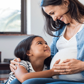 Pregnant mother smiling at young daughter