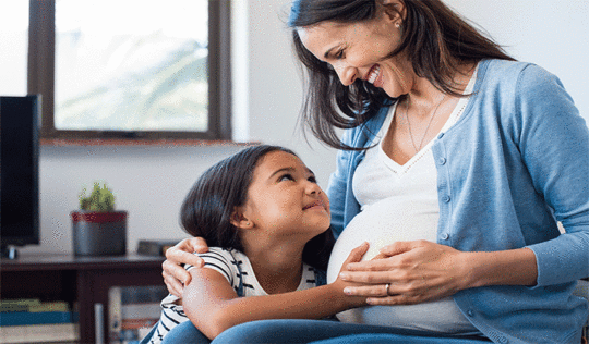 Pregnant mother smiling at young daughter