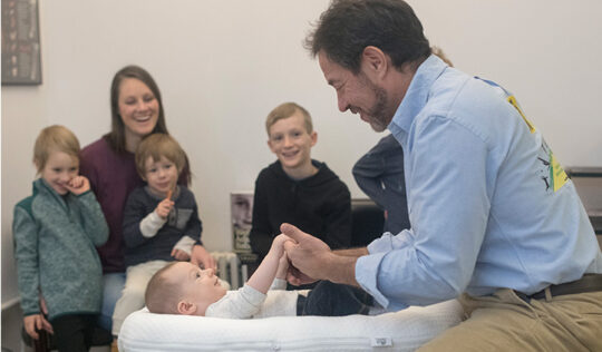 Dr Rubinstein adjusting a child with the family in the room at 57th St. Chiropractic in New York City.