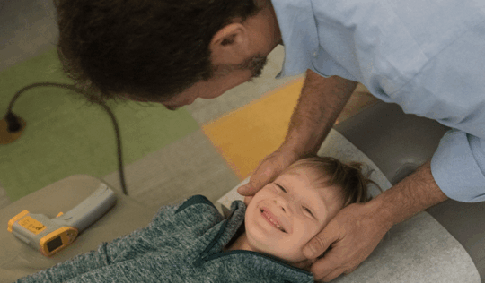 Young, smiling boy receiving a chiropractic adjustment from Dr Gregg Rubinstein at 57th Street Chiropractic in Manhattan.
