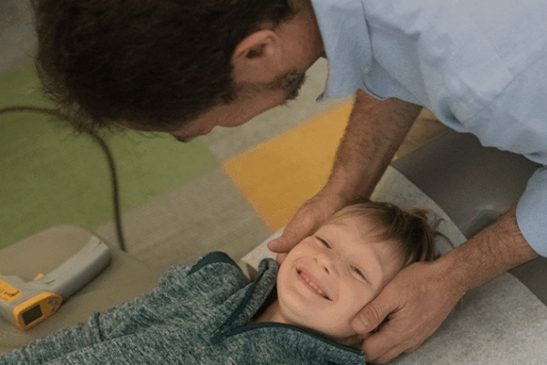 Young, smiling boy receiving a chiropractic adjustment from Dr Gregg Rubinstein at 57th Street Chiropractic in Manhattan.